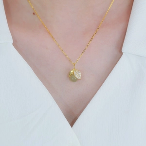 Elegant gold leaf pendant necklace with green jade bead shown on a model's neck