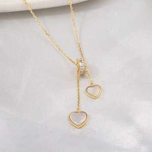 Collier avec double pendentif cœur en nacre dorée sur fond de soie blanche