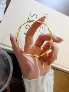 Golden Mobius twist bangle in polished titanium steel held in a cozy lifestyle setting