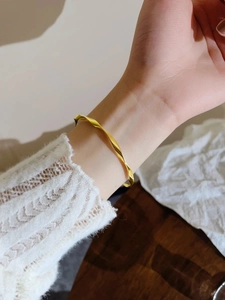 Elegant gold Möbius twist bangle in polished titanium steel for minimalist women's style