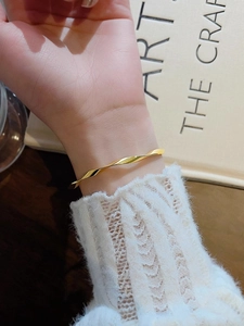 Gold Mobius twisted bangle in stainless steel worn with a cozy white knit sweater