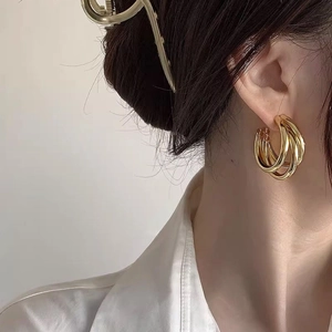 Eleganti orecchini a cerchio multistrato dorati per donna con un design minimalista a tre anelli