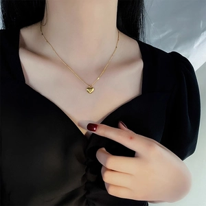 Elegant gold heart pendant necklace on model with polished metal finish and fine chain