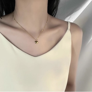 Close-up of a minimalist golden heart pendant necklace on a model's collarbone