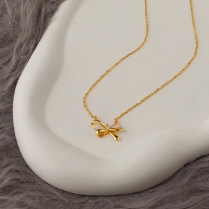 Elegante collana a fiocco dorata con ali occhio di gatto su vassoio in ceramica