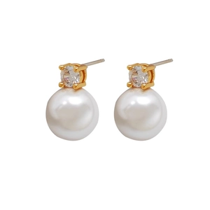 Elegant gold earrings with round white pearls and sparkling cubic zirconia on white background