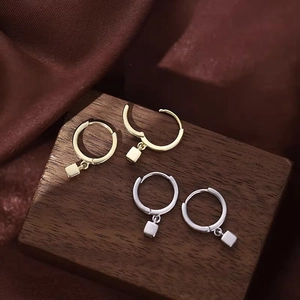 Créoles minimalistes en acier avec pendentifs cubes or et argent sur support en bois