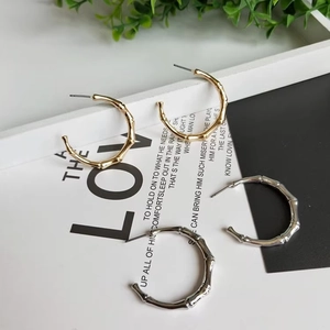 Bamboo style titanium steel hoop earrings in gold and silver finishes on white tray