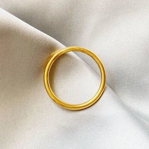 Minimalist matte gold finish solid band ring on elegant grey silk fabric background