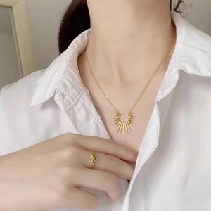 Golden sunburst pendant necklace and heart open ring set worn on a model in white shirt