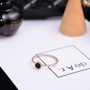 Minimalist 6mm rose gold titanium ring with a round black inlay on elegant display