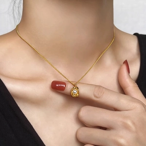 Minimalist gold titanium necklace with pearl peanut pendant worn by a model