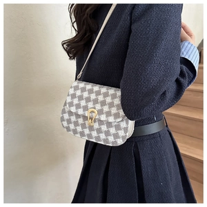 Detail of crossbody saddle bag featuring houndstooth pattern and metal horseshoe buckle