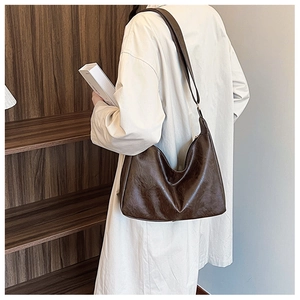 Detail of a deep brown vintage faux leather shoulder bag with adjustable strap