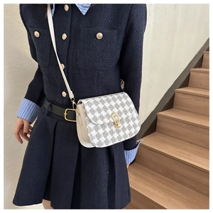 Close-up of houndstooth crossbody bag with golden horseshoe buckle on a female model
