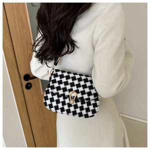 Close-up of black and white houndstooth wool saddle bag with golden horseshoe buckle