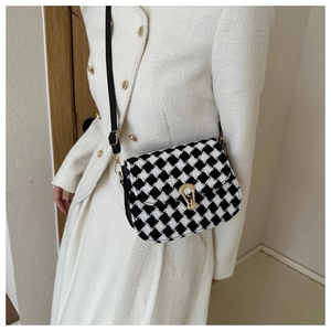 Detail shot of black and white houndstooth plaid saddle bag with golden U-shaped buckle