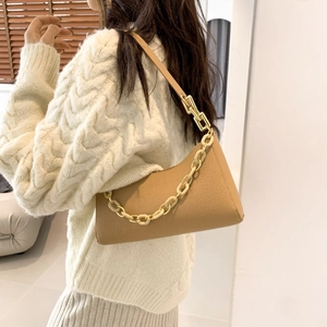 Brown crocodile embossed baguette bag with cream chain strap on model's shoulder