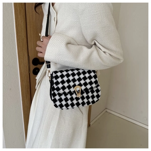 Detail of classic houndstooth saddle bag with elegant gold buckle and leather strap
