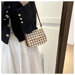 Detail of houndstooth crossbody bag featuring golden U-shaped clasp and brown strap