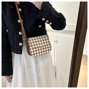 Detail of vintage brown houndstooth saddle bag with gold U-shaped metal lock