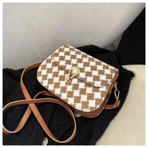 Detail of vintage plaid saddle bag with gold horsebit buckle and brown leather trim