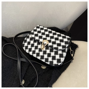 Close-up of houndstooth wool fabric texture and gold metal lock on the saddle bag