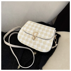 Detail of checkered woven saddle bag with gold horseshoe clasp and leather strap