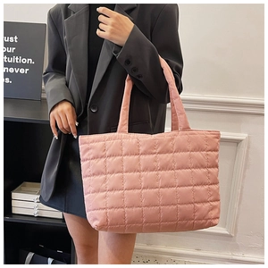 Macro detail of pink quilted tote bag showing large square stitching and soft satin texture