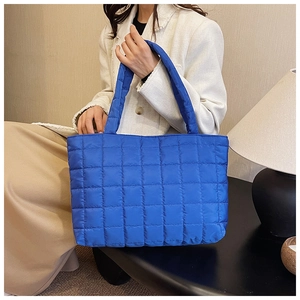 Close-up of royal blue quilted tote bag fabric with square stitching and glossy texture