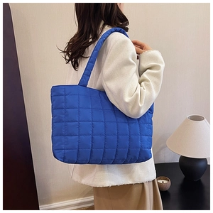 Detailed view of blue quilted tote bag worn by model showing its large capacity and strap
