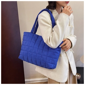 Detail of navy blue quilted tote bag on shoulder, showing spacious nylon padded design