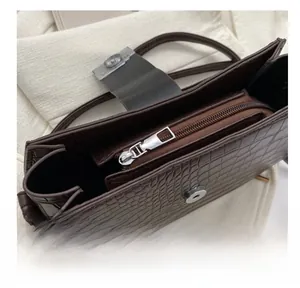 Detailansicht von Silberreißverschluss und Kroko-Prägung an dunkelbrauner Tasche
