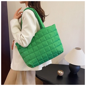 Close-up of vibrant green quilted nylon puffer tote bag with soft padded texture