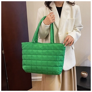 Detail of bright green quilted tote bag showing soft padded texture and large capacity