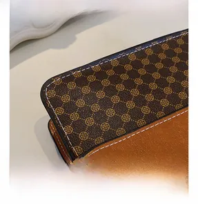 Detailed macro view of monogram canvas and orange-brown leather stitching on crossbody bag