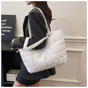 Detail of white quilted down tote bag with diamond pattern and soft padded shoulder strap