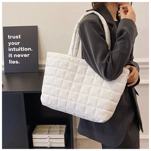 Detailed view of white quilted tote bag featuring a padded texture and square stitching