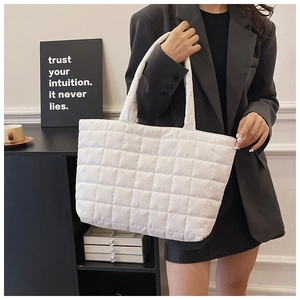 Detail of white quilted tote bag featuring classic diamond stitching and padded straps