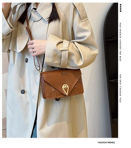 Detail shot of brown leather bag with golden triangle lock and vintage envelope flap