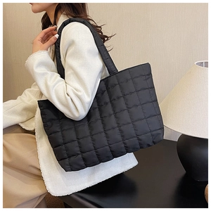 Close-up of black quilted nylon tote bag showing square stitching and soft padded texture
