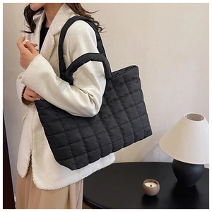 Close-up of a black quilted puffer tote bag shown on a model for daily lifestyle use
