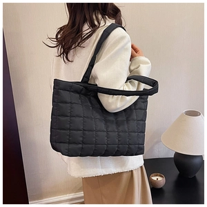 Detailed view of the thick padded handle and black quilted stitching of the tote bag