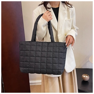 Detail shot of the black quilted texture and soft padded fabric on the oversized tote bag