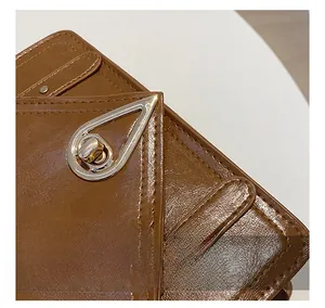 Macro shot of brown pebble grain leather bag featuring a silver teardrop metal clasp