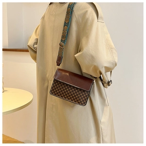 Detail of vintage square crossbody bag with patterned body and wide bohemian strap