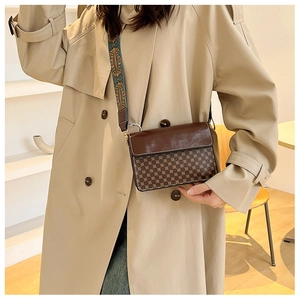Close-up of retro brown crossbody bag with patterned wide strap and geometric detailing
