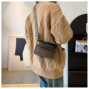 Detail of a vintage checkered crossbody bag with wide bohemian embroidered strap on a model