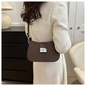 Detail der dunkelbraunen Schultertasche mit Krokoprägung und silberner Schnalle am Model