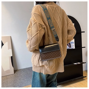 Detail of vintage crossbody bag with wide bohemian strap on model's shoulder